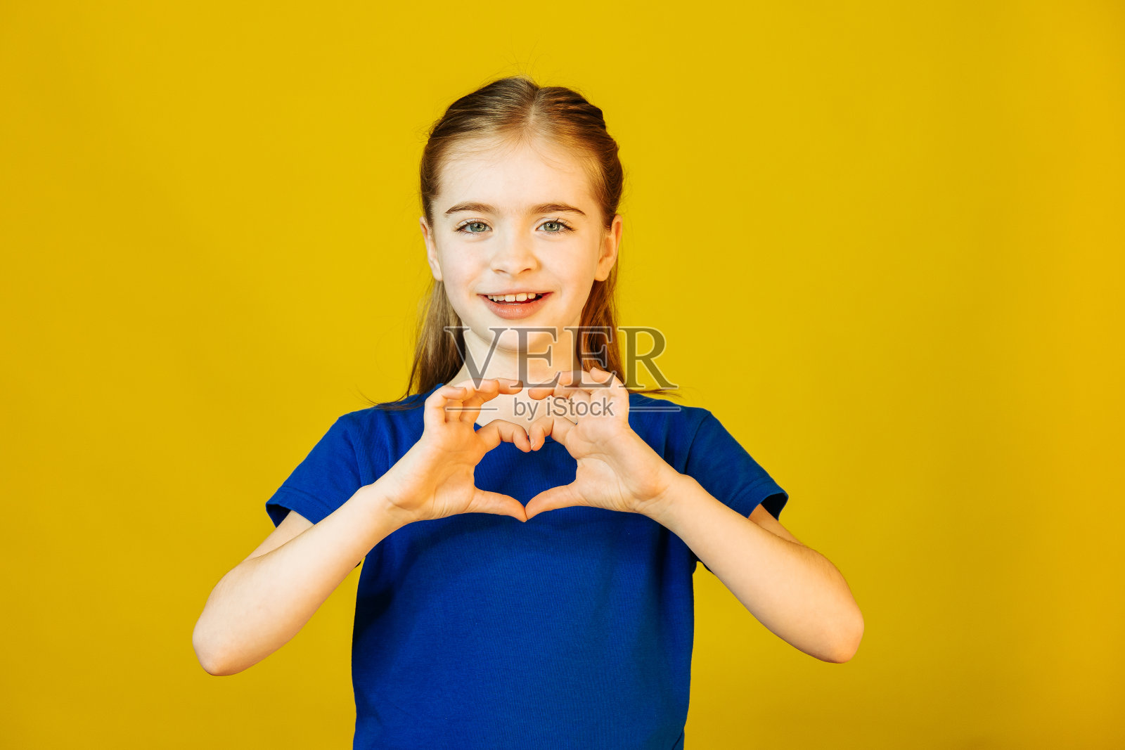 孩子看着相机,用手做心形手势照片摄影图片