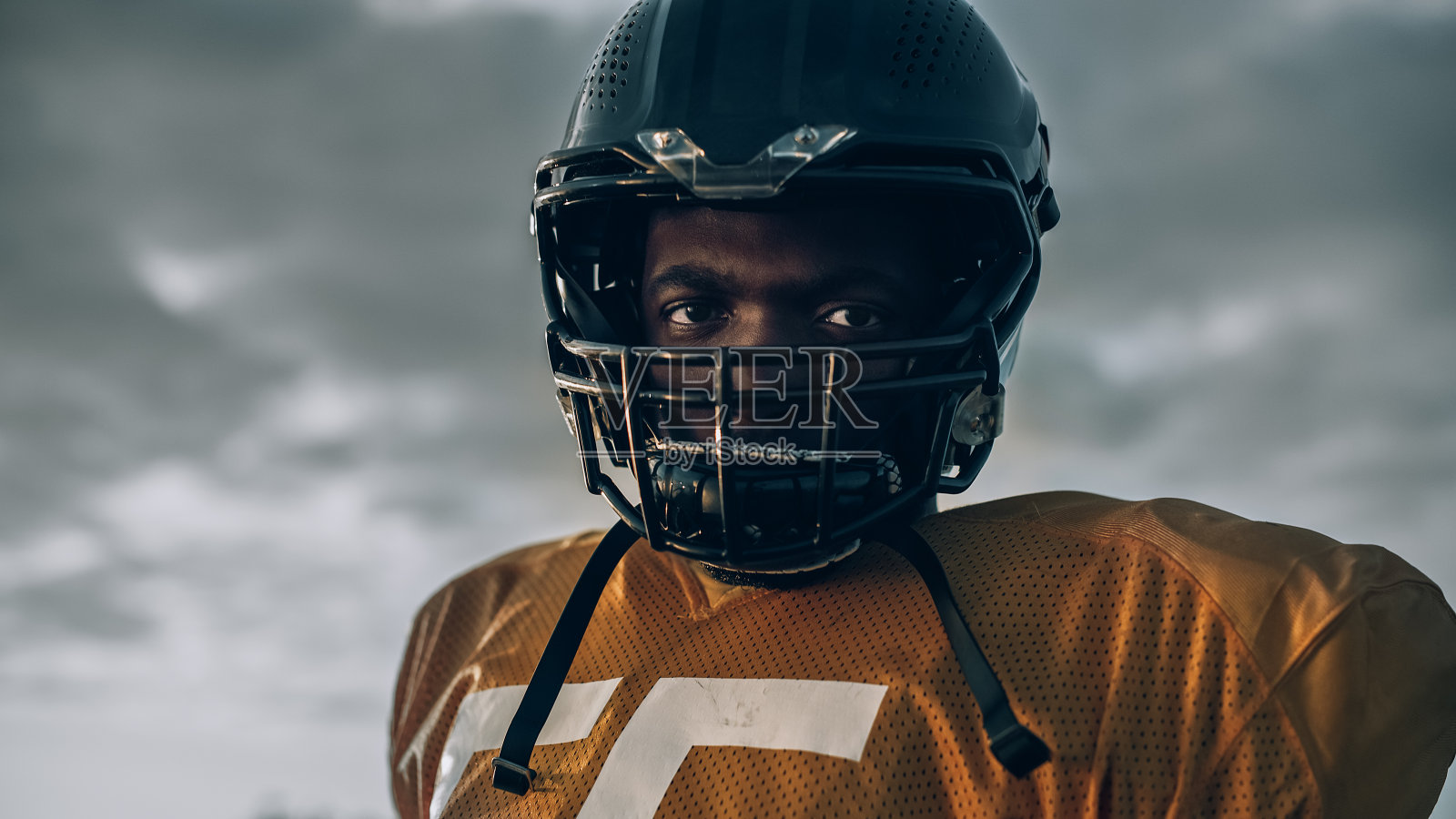美国橄榄球锦标赛:职业球员戴头盔的特写。充满力量,技巧,决心取胜的职业运动员。低角度拍摄照片摄影图片