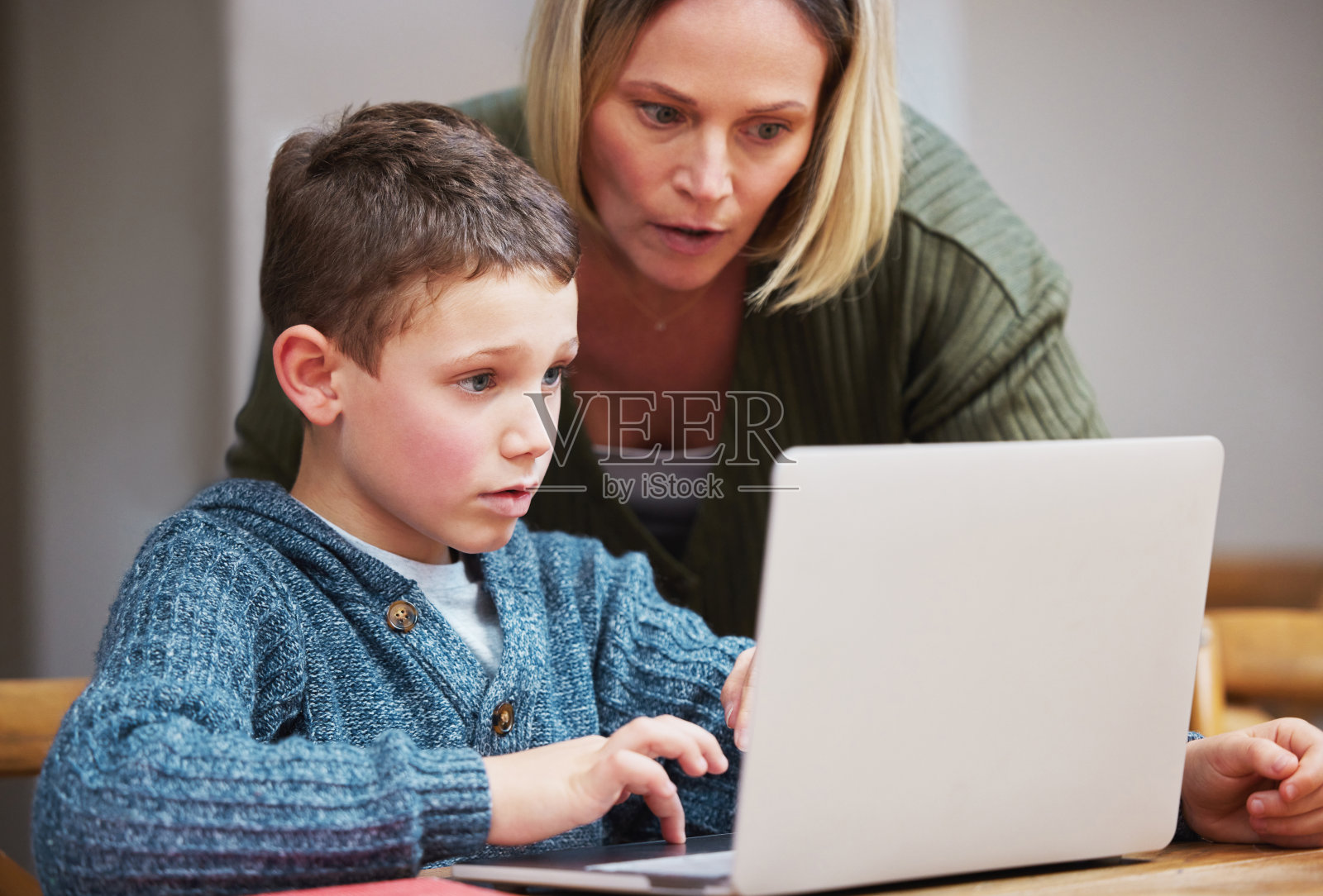 一位母亲用笔记本电脑帮助儿子完成家庭作业照片摄影图片