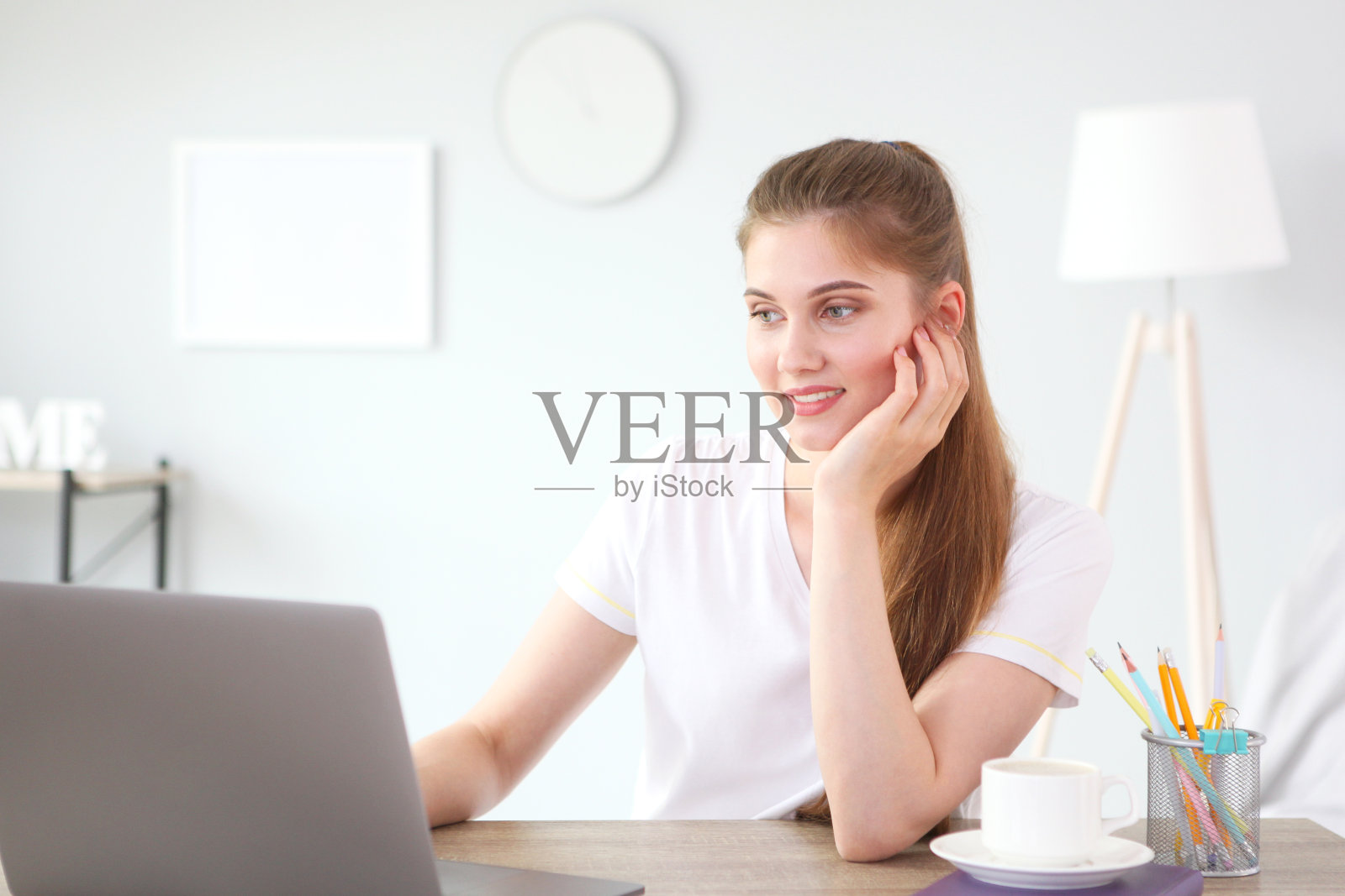 这个女孩在家里用一台现代笔记本电脑远程工作。照片摄影图片