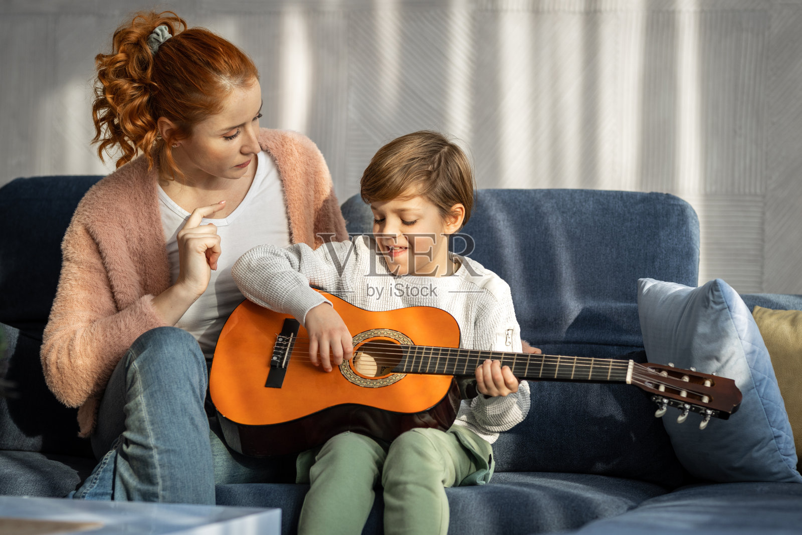 母亲在家教儿子弹吉他照片摄影图片