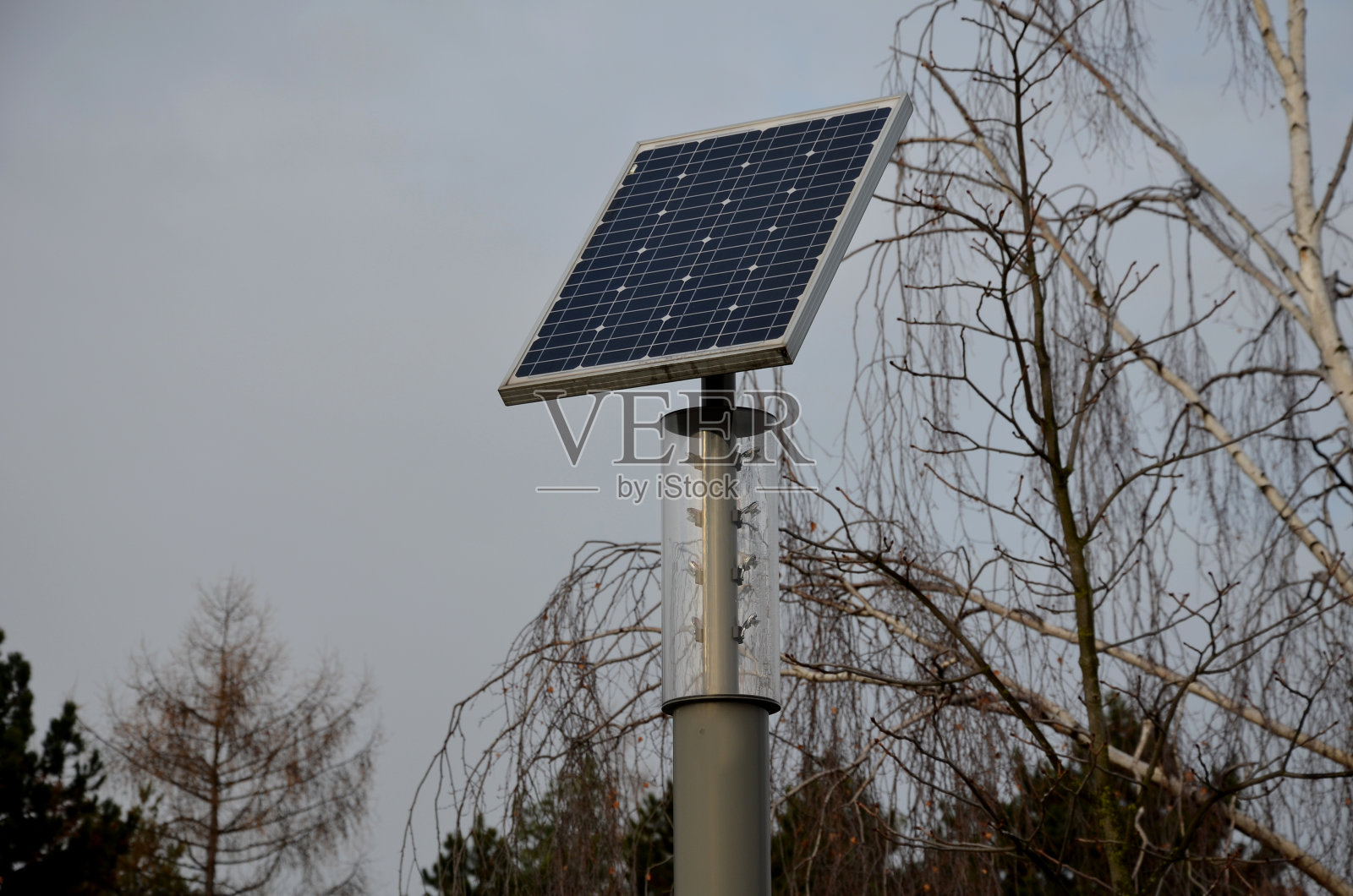 灰色不锈钢圆柱状。这是一盏有透明罩和LED灯泡的灯。在路灯的顶部有一个小的太阳能电池板。公园照片摄影图片