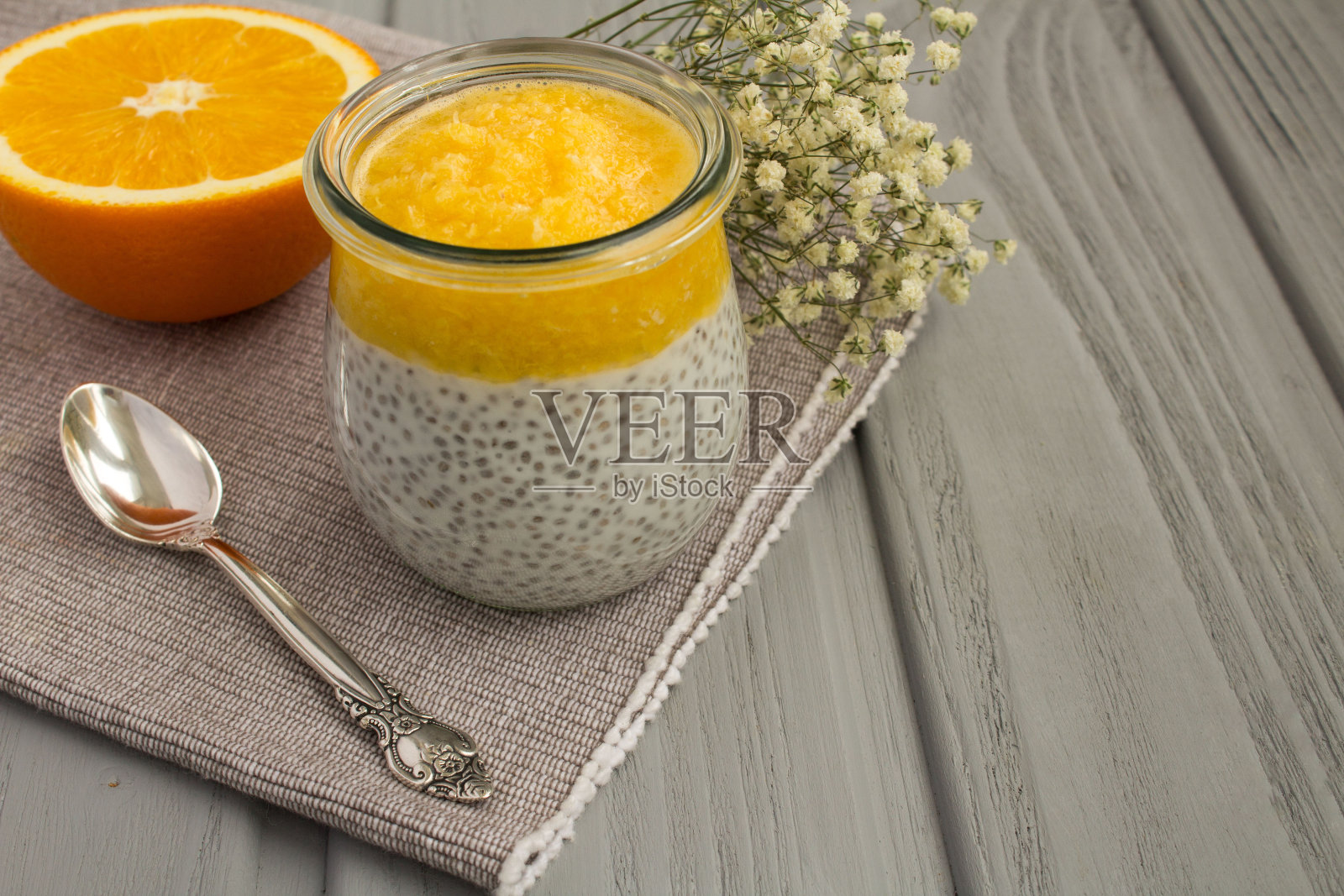 带有奇异籽和橙色的灰色木制背景的布丁。特写镜头。照片摄影图片