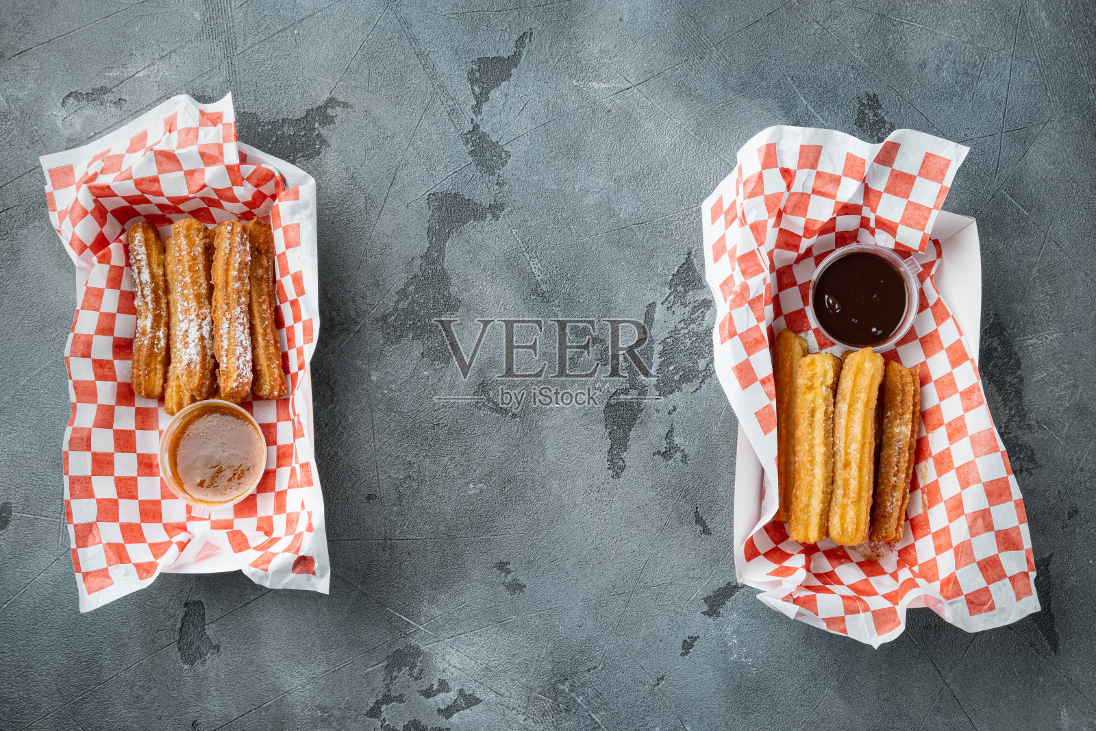 美味的热甜油条在纸上与巧克力和焦糖在纸盘上,在灰色的背景,顶视图平躺与文字空间,copyspace照片摄影图片