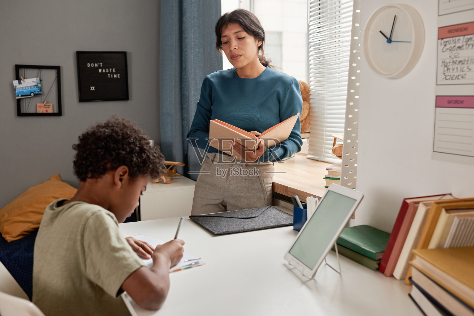 一个非裔美国男孩在准备考试时,坐在桌边和导师一起听写照片摄影图片