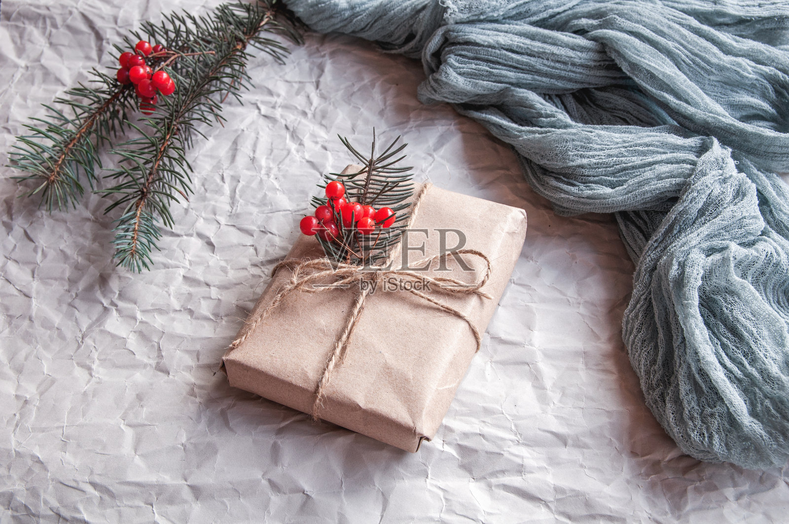 礼品盒旁边的复古桌布灰色和云杉树叶与红色浆果在一个黑色的背景照片摄影图片