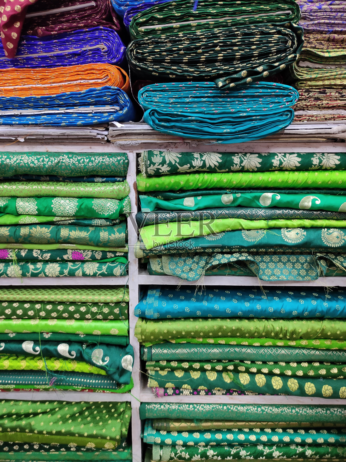 商店里有一卷卷的织物和纺织品。市场上有多种颜色的印度图案。印度马哈拉施特拉邦浦那的布店。照片摄影图片
