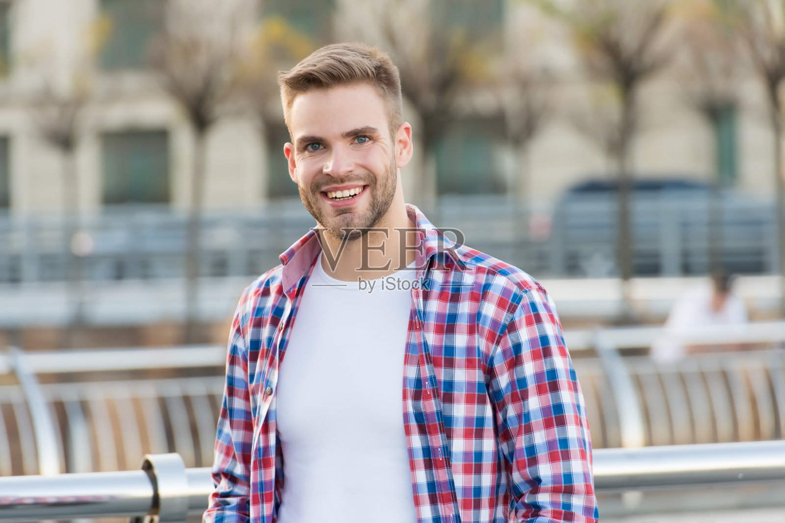 快乐的英俊的家伙与nice微笑穿着休闲格子衬衫户外和有鬃毛在未刮的脸,男性时尚和修饰照片摄影图片