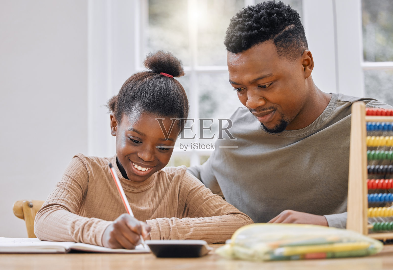 一个年轻的父亲在家里帮助他的女儿做作业照片摄影图片