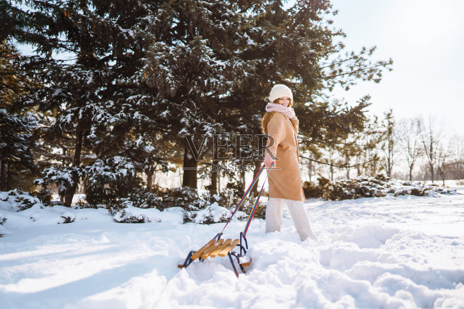 一个年轻的女人在冬天积雪的森林里滑着雪橇。照片摄影图片