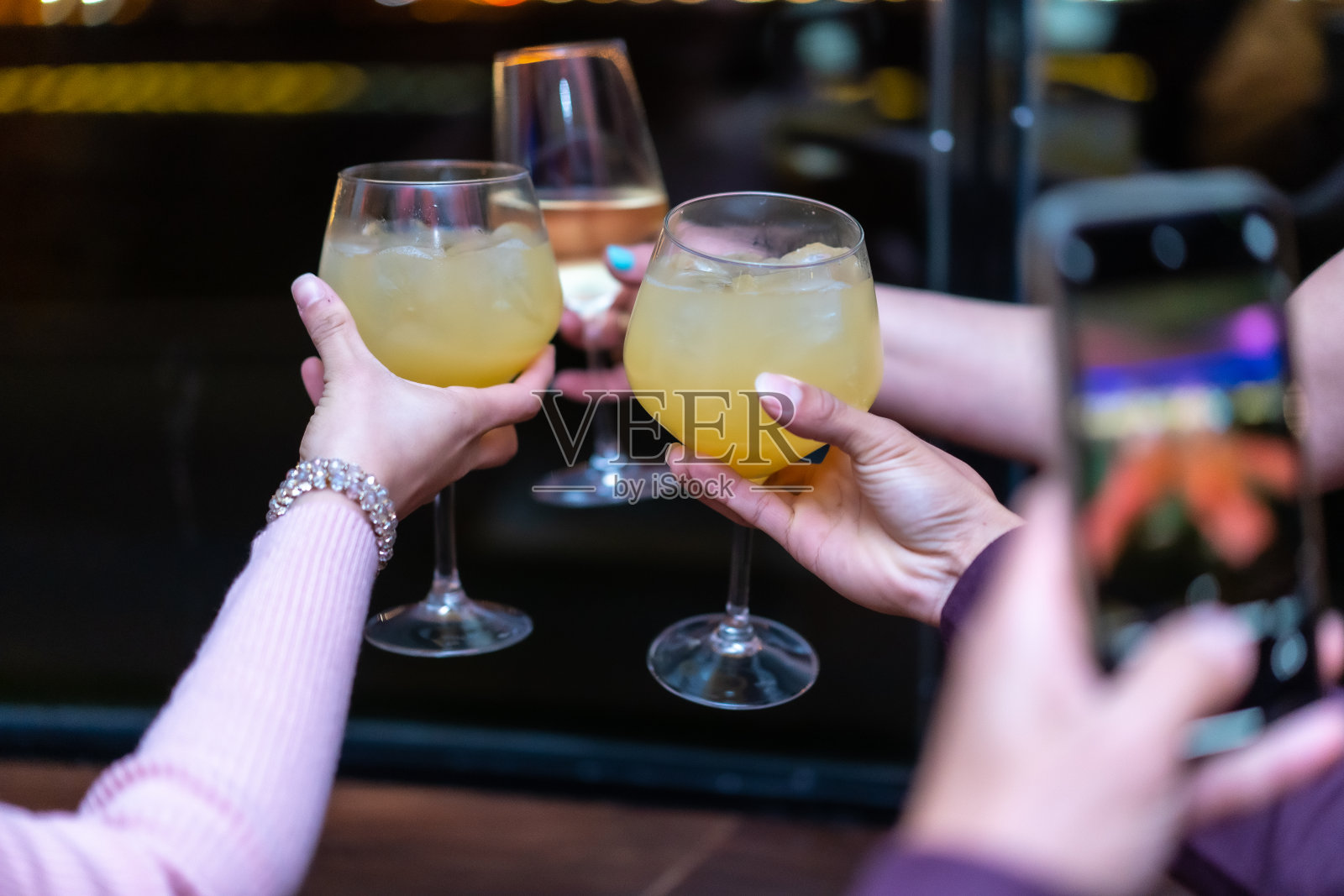 在夜总会喝酒,朋友们正在享受一个聚会,他们的杯子,呼喊橙汁和金汤力照片摄影图片