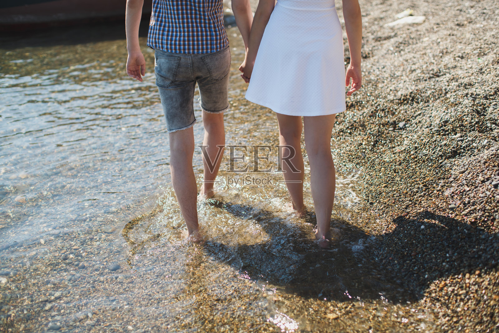 年轻男女手牵着手,赤脚在水上行走照片摄影图片
