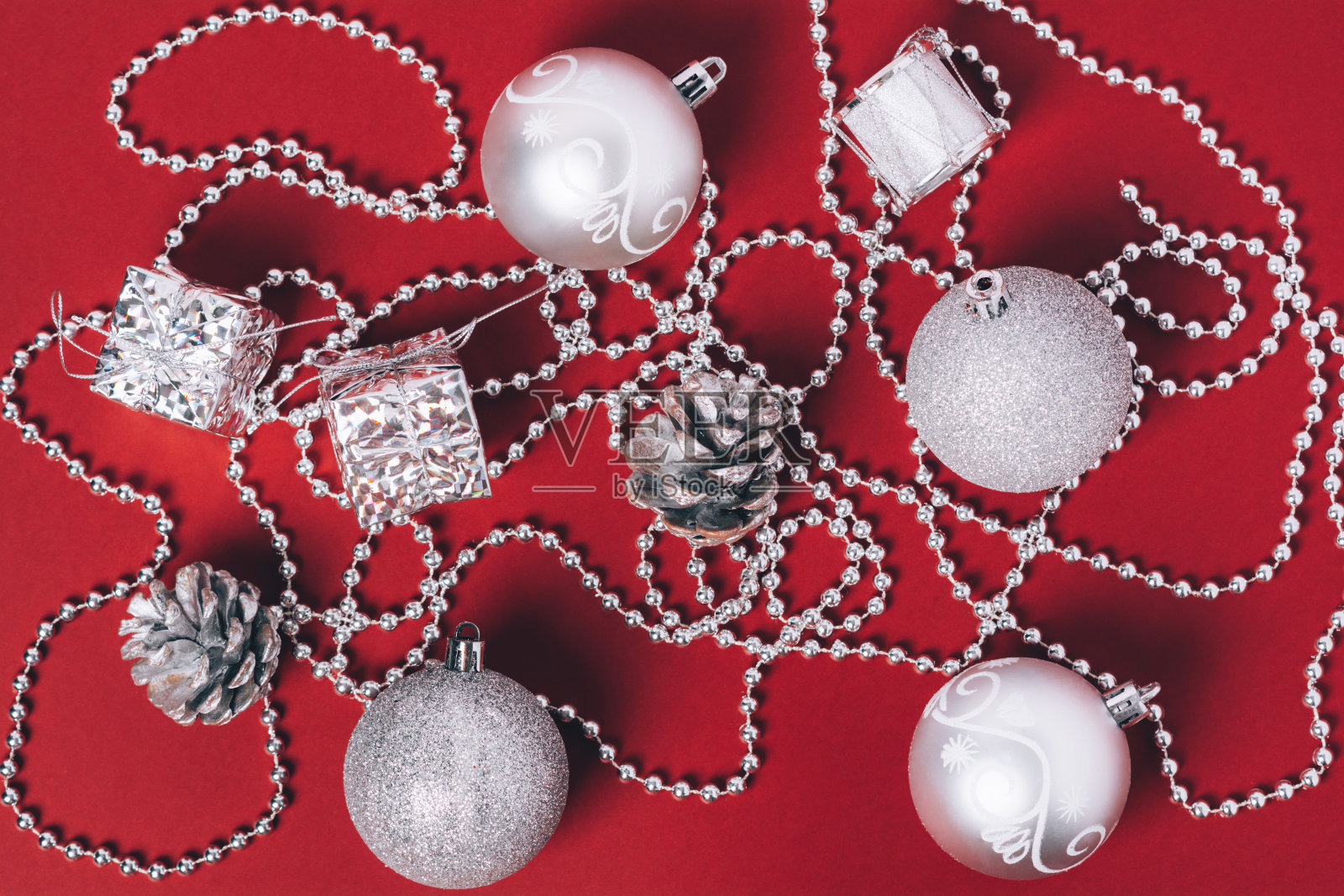 红色背景上的银色圣诞装饰物。照片摄影图片