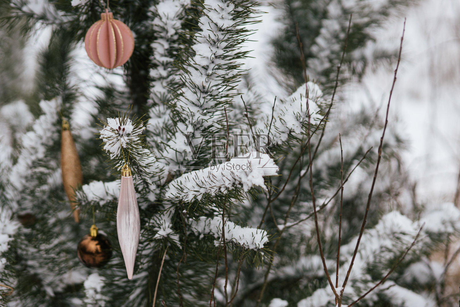 现代圣诞装饰品挂在雪白的松树树枝上。在雪地里用时髦的小玩意装饰圣诞树。农村的寒假。圣诞快乐!空间的文本照片摄影图片