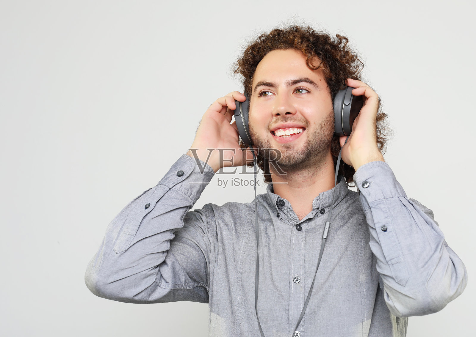 享受音乐的声音。工作室肖像英俊的年轻人与耳机照片摄影图片