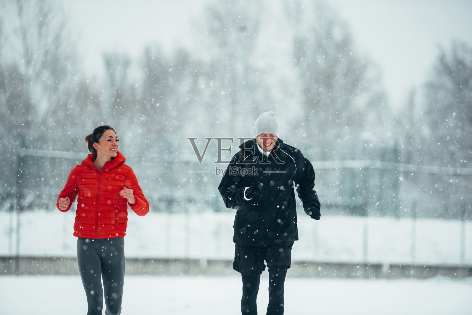 一对年轻夫妇在雪天一起跑步照片摄影图片