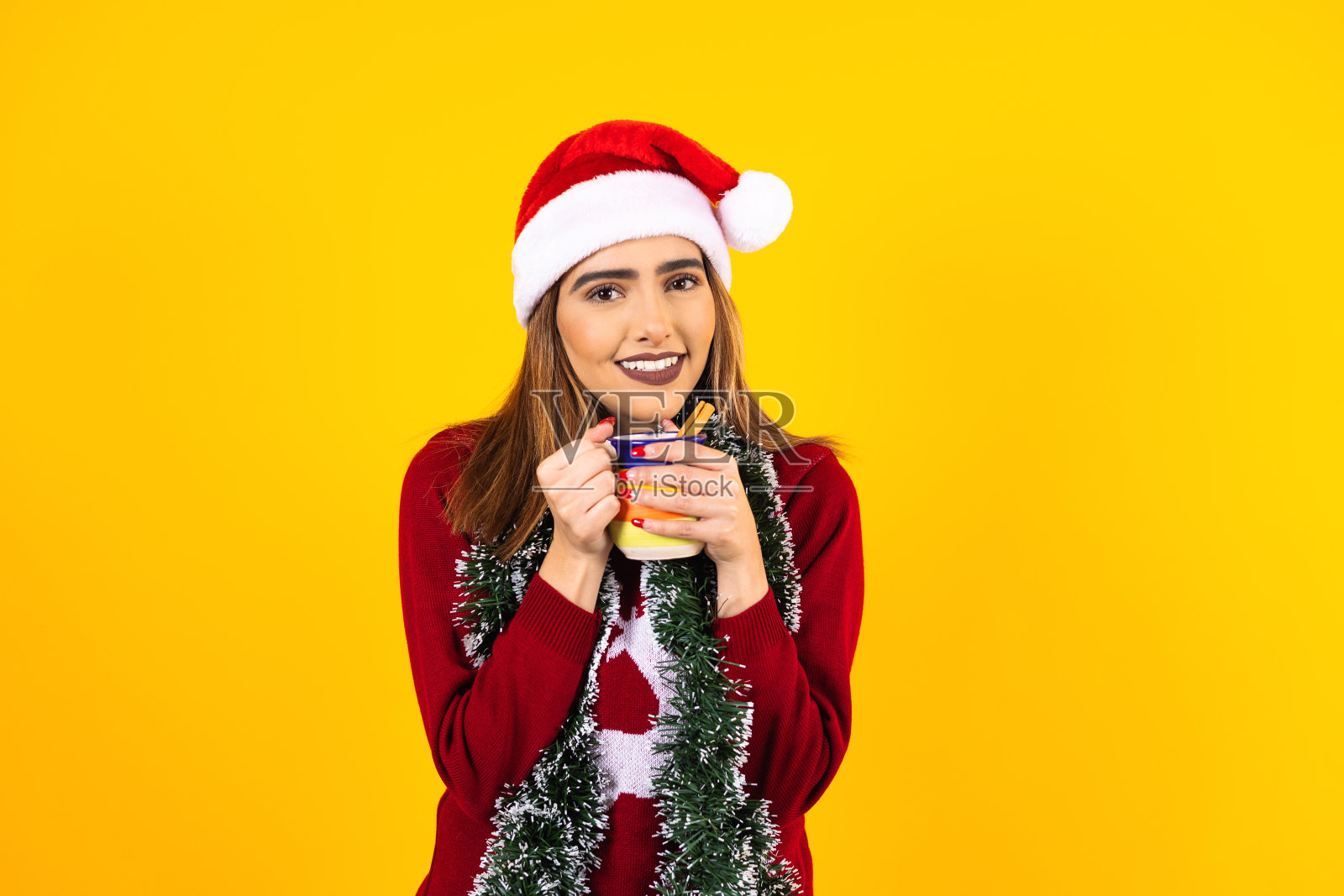 年轻的拉丁美洲妇女肖像戴圣诞帽在黄色的背景在墨西哥拉丁美洲照片摄影图片