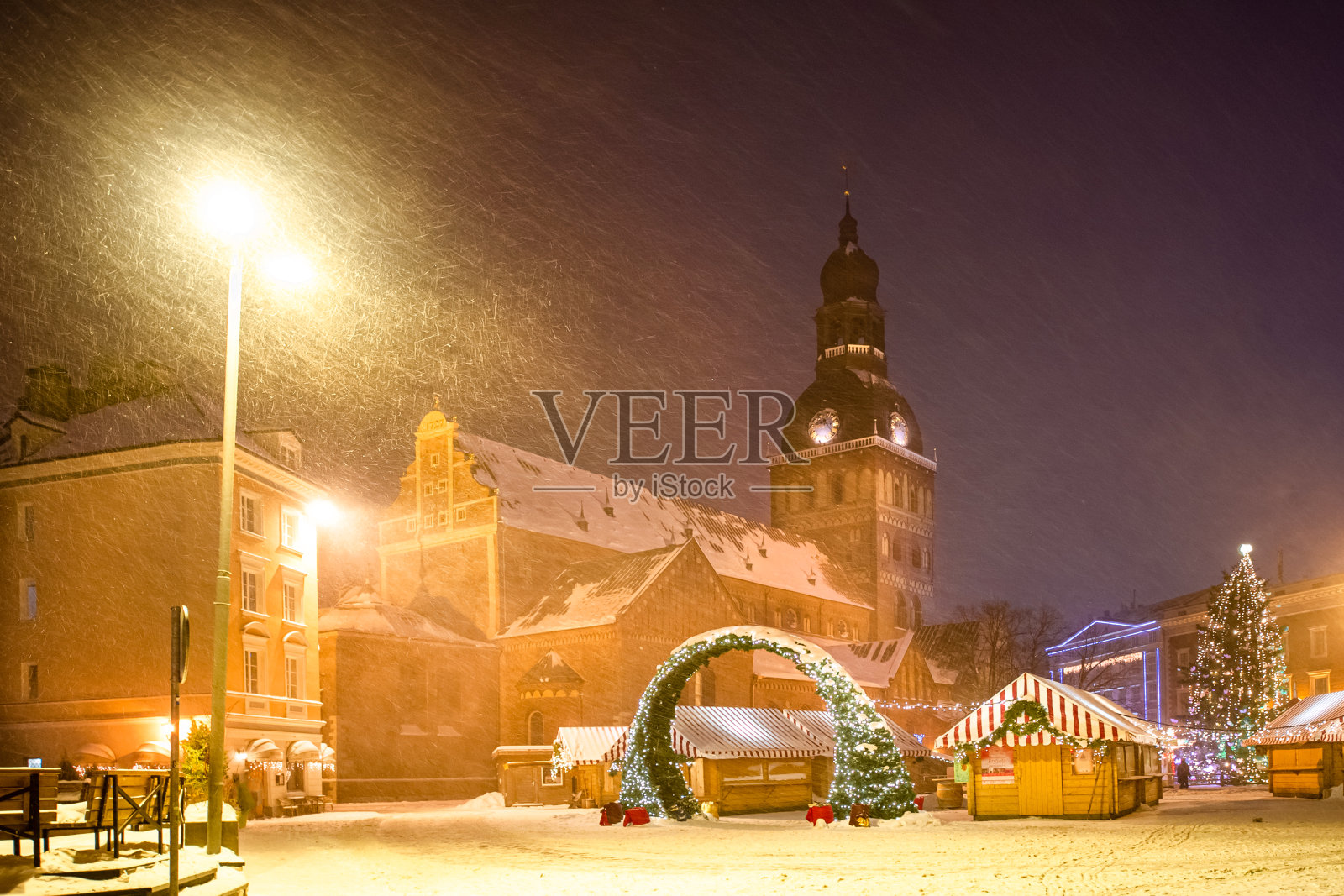 冬季的傍晚,城市的主要广场上,街道上被夜晚的灯光点亮,圣诞节前,新年。圣诞节的公平。天主教堂、教堂、高塔。雪的街道。里加,拉脱维亚。照片摄影图片