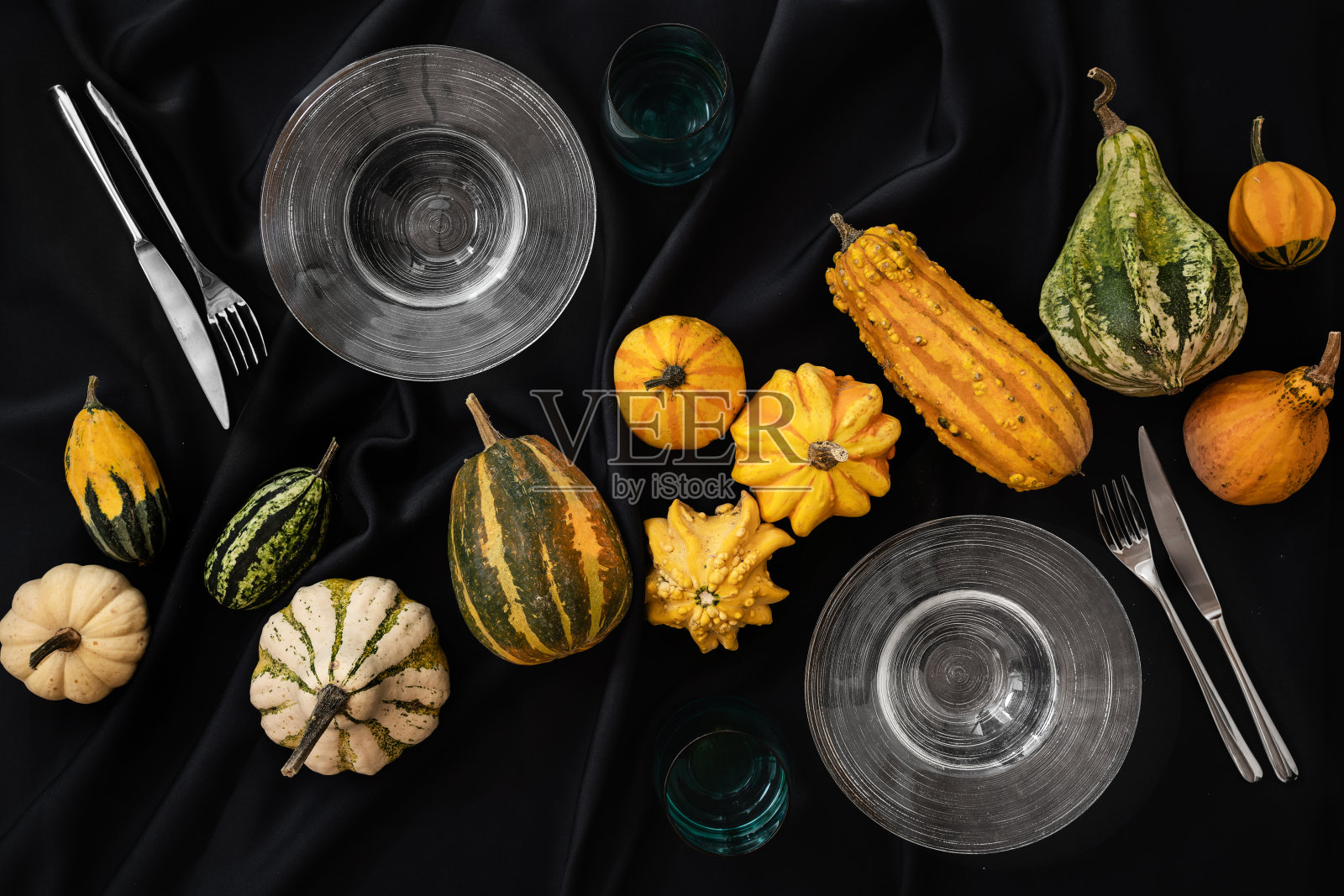 桌子上铺着黑色的万圣节桌布,上面有南瓜,还有一套盘子和餐具照片摄影图片