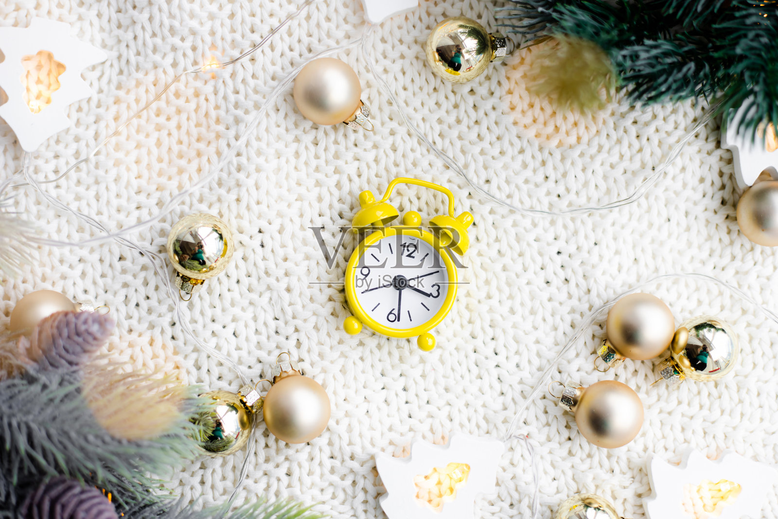 一个带花环的格子闹钟。黄色的闹钟。舒适的氛围。家里舒适。新年和圣诞节。照片摄影图片