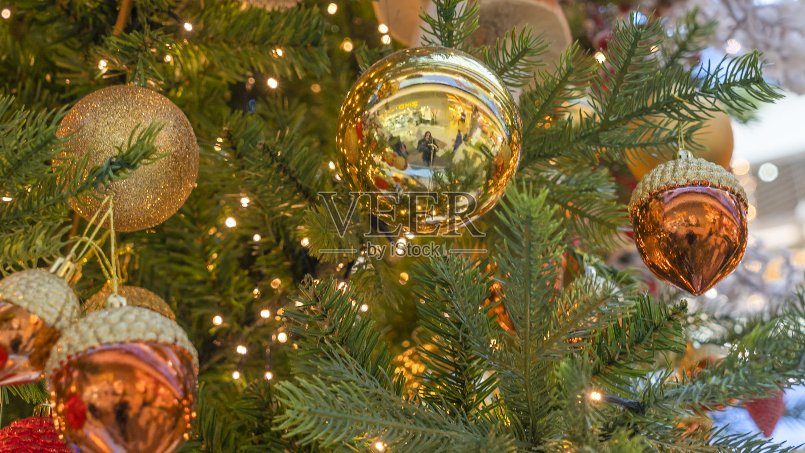 传统的人造圣诞树,背景是圣诞玩具、彩球和发光的彩灯。圣诞节的概念。照片摄影图片