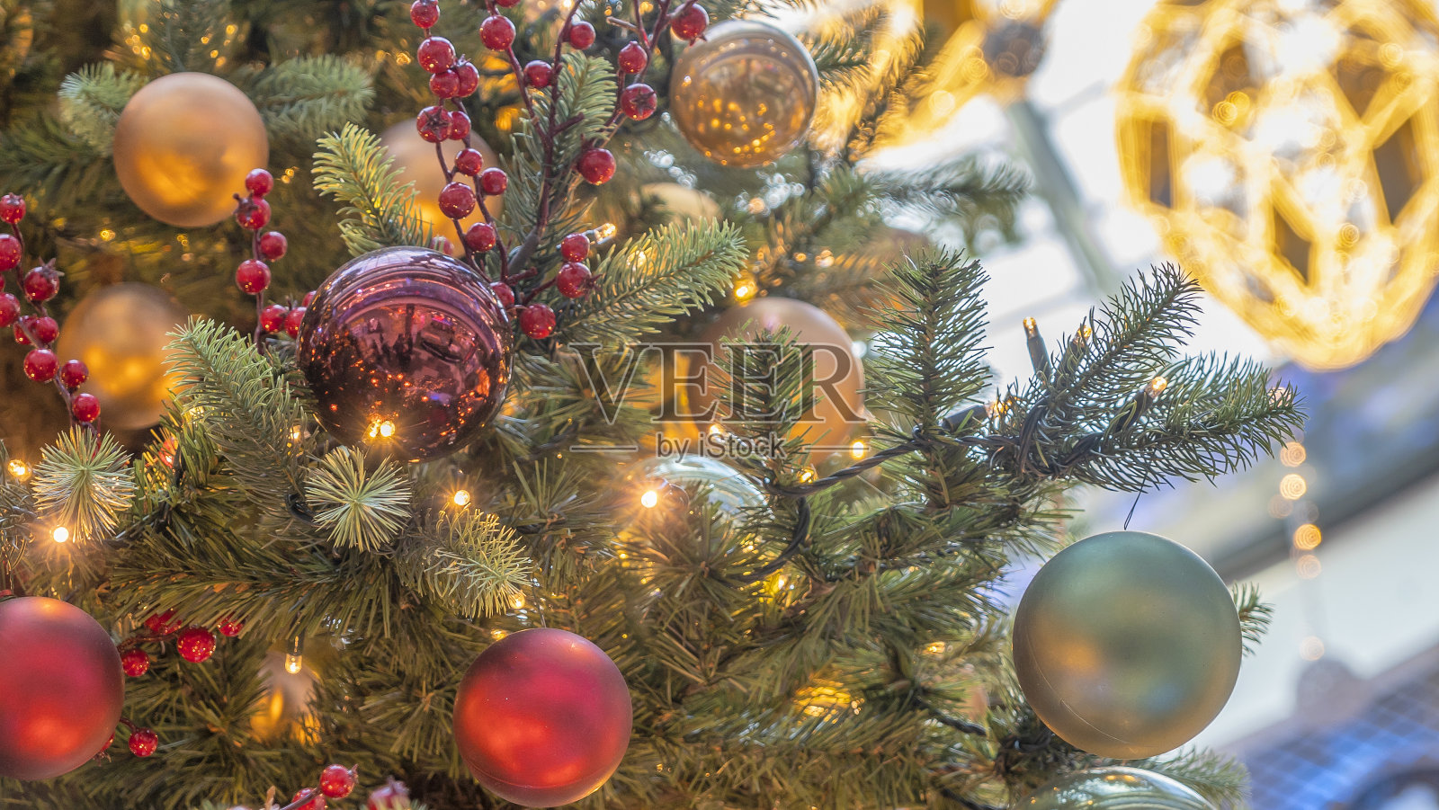 传统的人造圣诞树,背景是圣诞玩具、彩球和发光的彩灯。圣诞节的概念。照片摄影图片