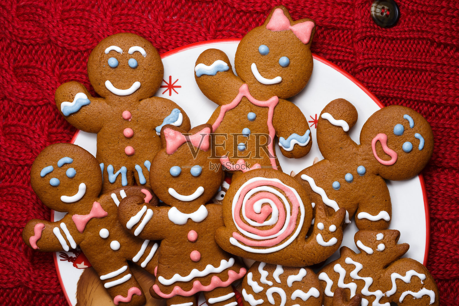 微笑的姜饼男依偎在节日的菜肴中。一套圣诞节自制饼干照片摄影图片