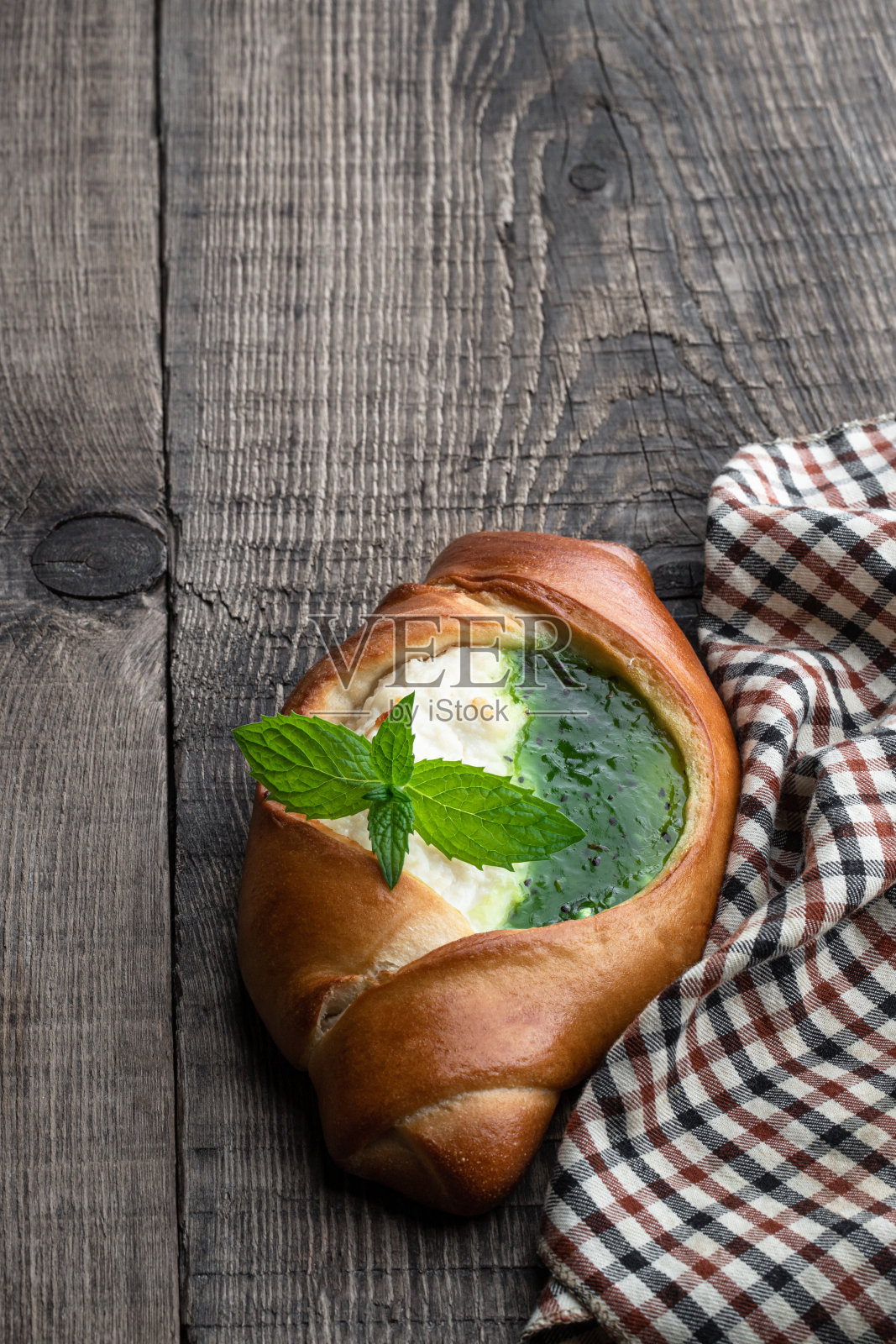 木桌上新鲜出炉的小圆面包,配上白软干酪和猕猴桃果酱照片摄影图片