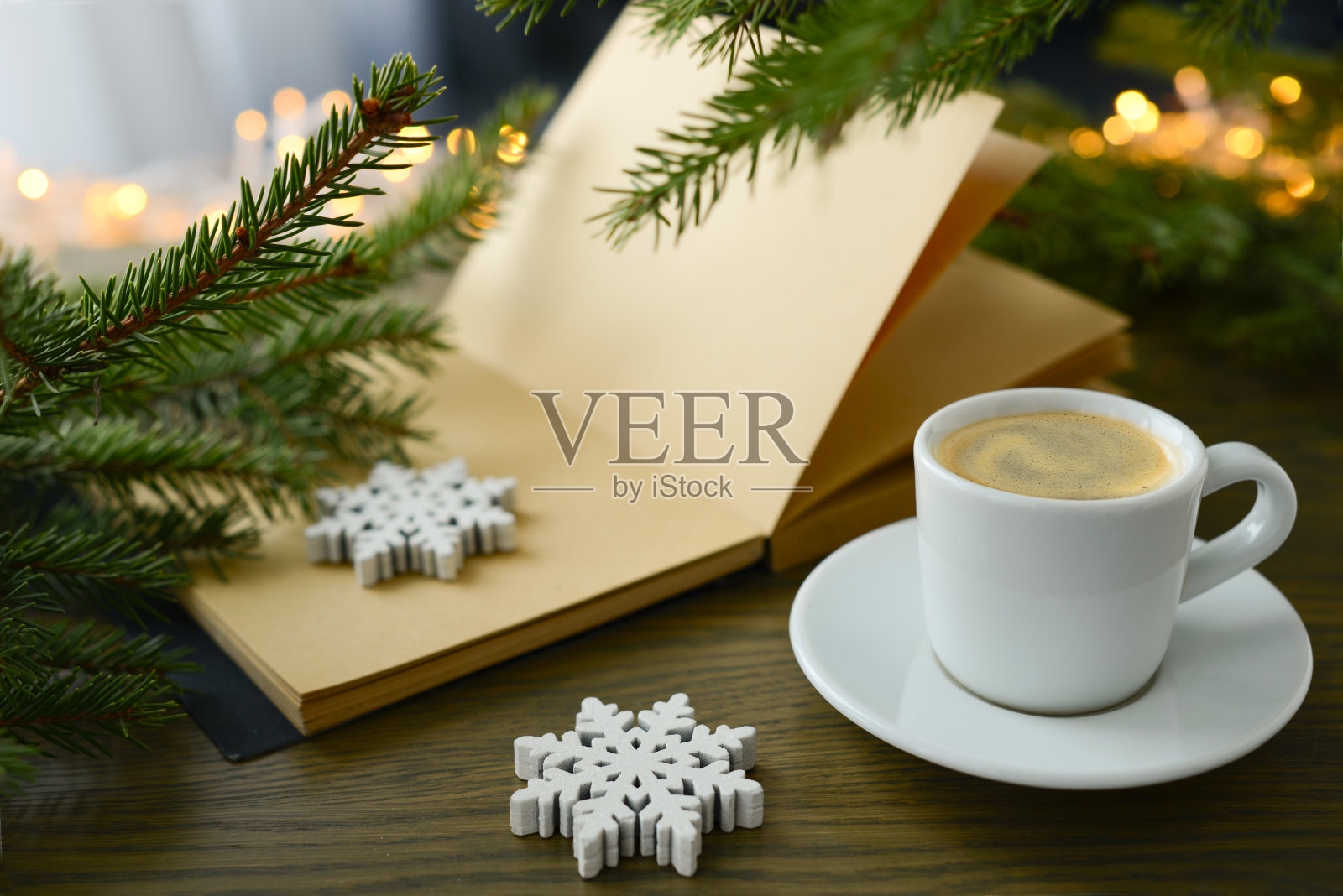 圣诞节或冬天的咖啡。咖啡杯、书、圣诞树和圣诞彩灯,金色的散景,模糊的背景。冬日的喜庆气氛和黑咖啡,热腾腾的香气在圣诞之际畅饮照片摄影图片