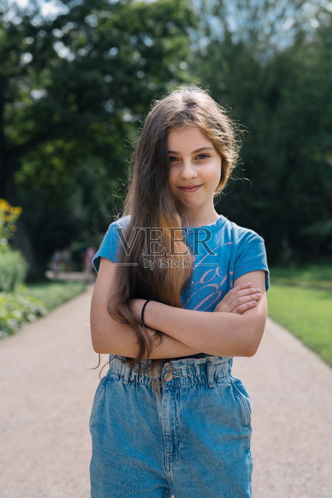 一个十岁的俄罗斯女孩双臂交叉站在城市公园里的垂直画像照片摄影图片