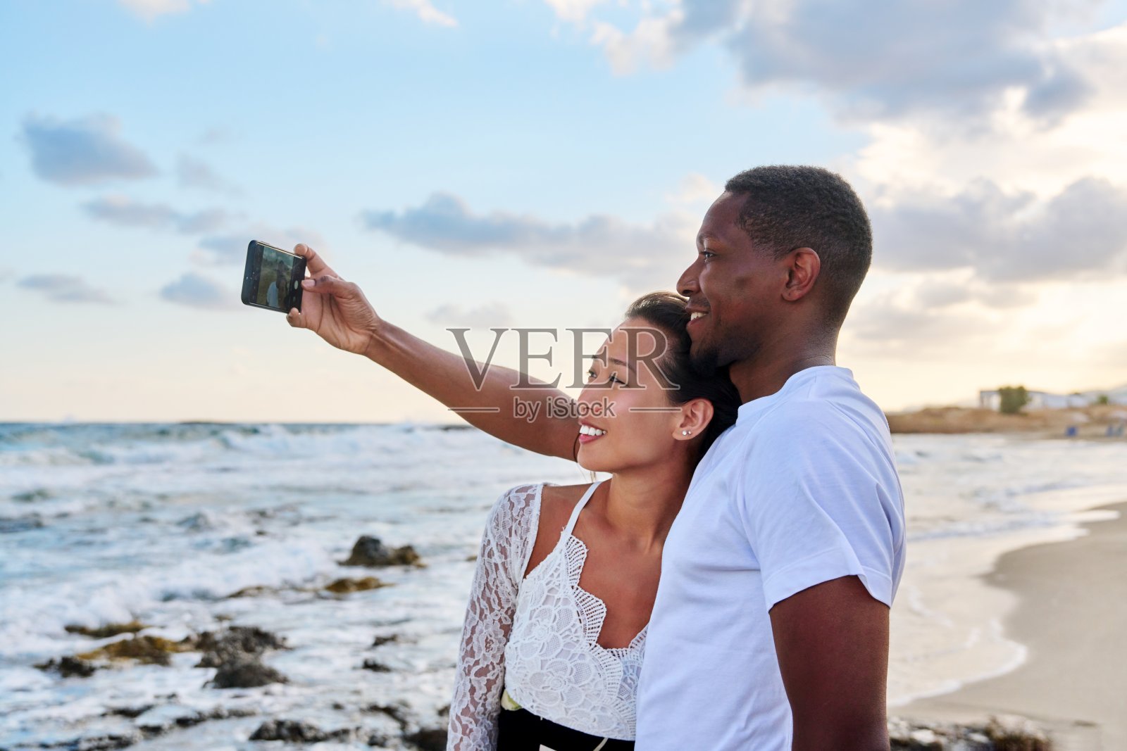 幸福的情侣在沙滩上用智能手机自拍照片摄影图片