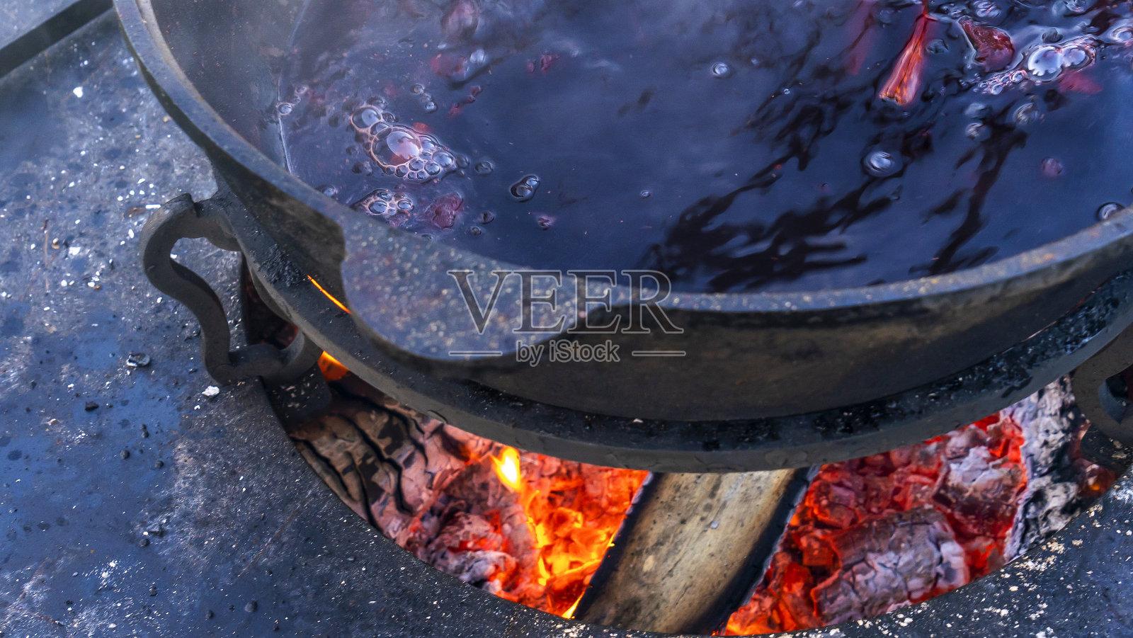 在大锅中加热葡萄酒。热酒在大锅里煮。传统节日里的维生素。照片摄影图片