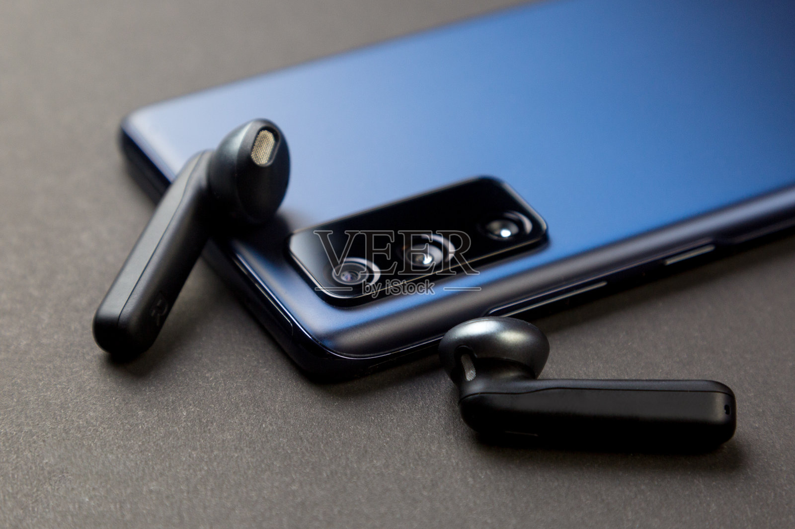 无线的黑色耳机和灰色背景上的电话-一个现成的新年礼物照片摄影图片