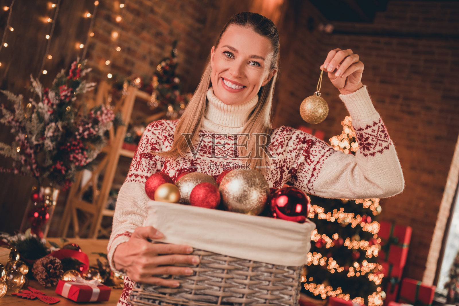 照片甜蜜迷人的成熟女人穿印花毛衣微笑装饰新年树在室内房子的房间照片摄影图片