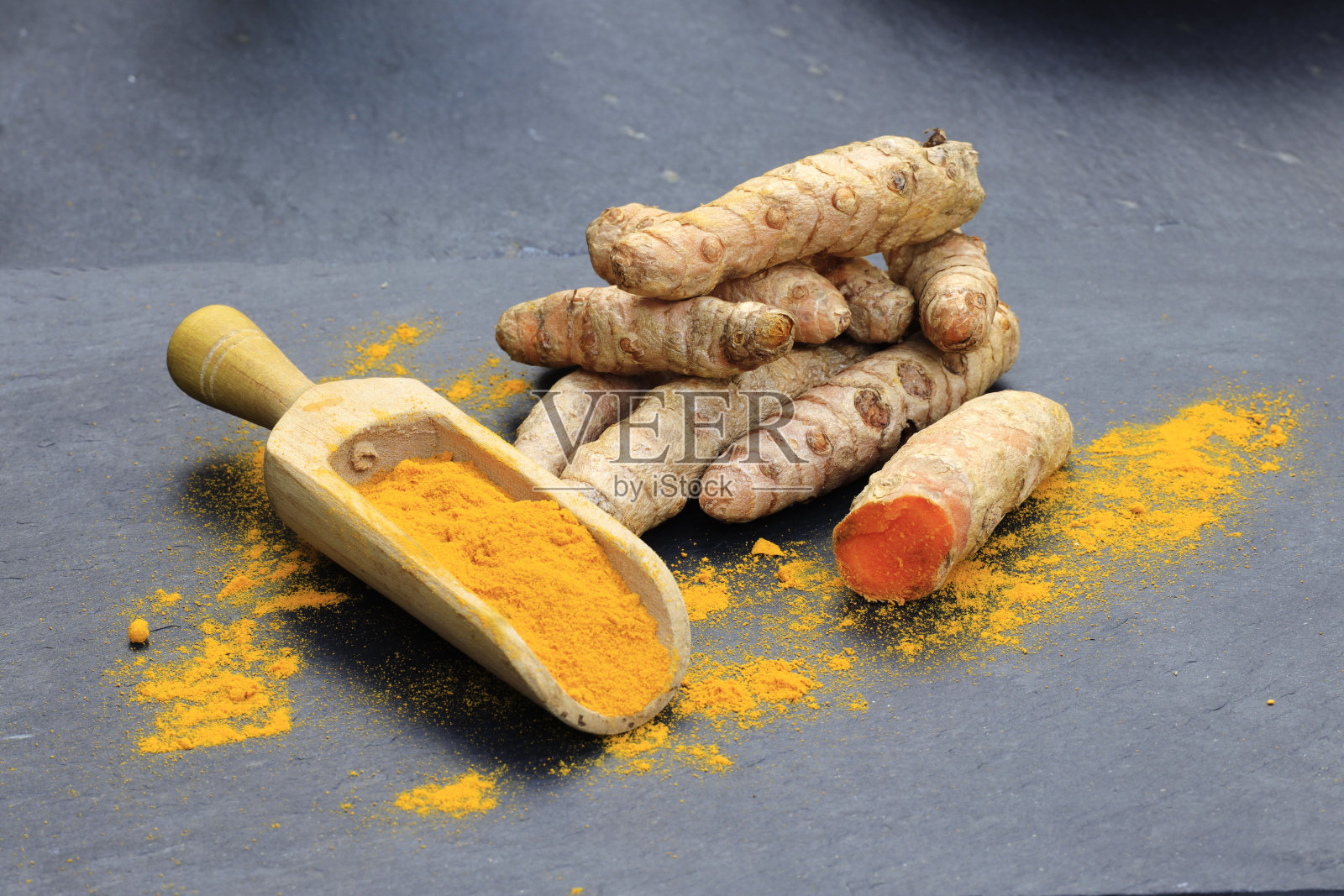 姜黄粉在木勺和根上一个黑色的桌子(姜黄隆),Kurkuma照片摄影图片