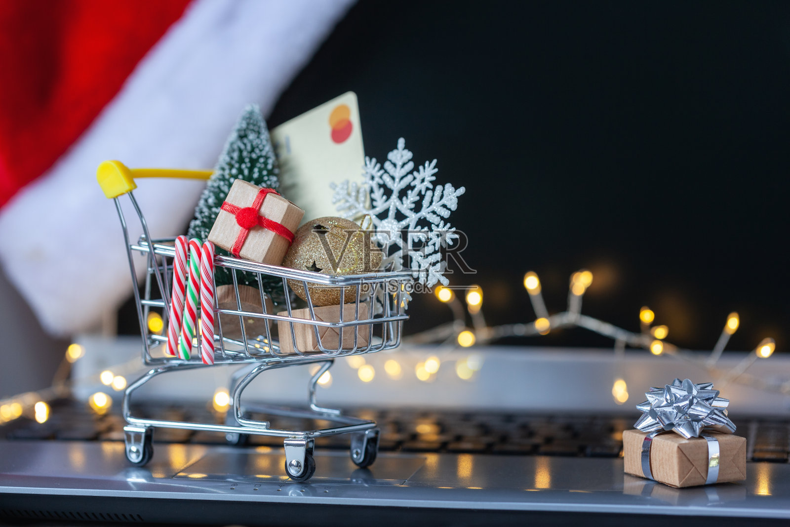 装满礼品盒的购物车和笔记本电脑键盘上的圣诞树。概念网上购物和假日销售。照片摄影图片