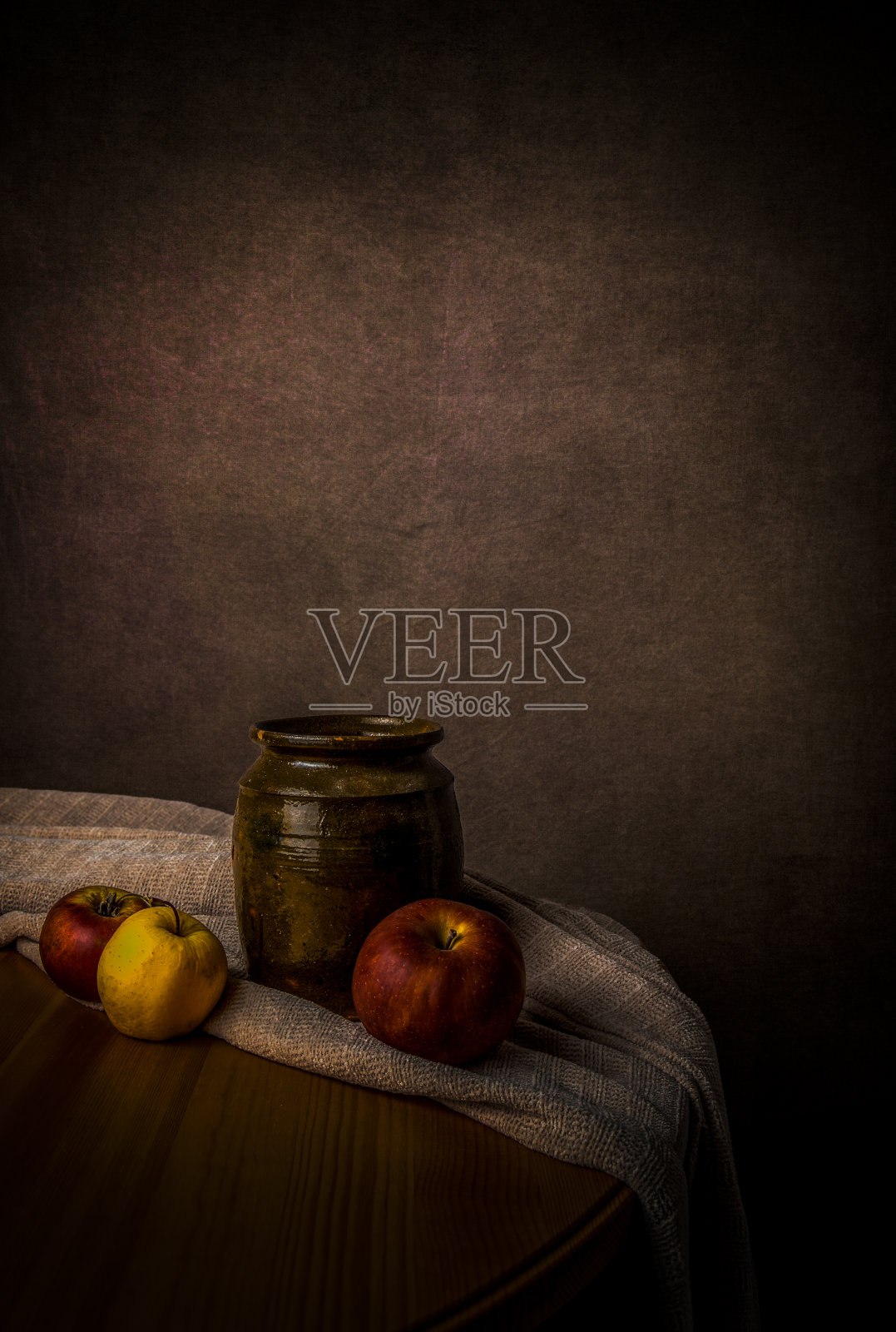 静物画中有旧水罐、三个苹果和一张桌子上的布。艺术与油画概念。照片摄影图片