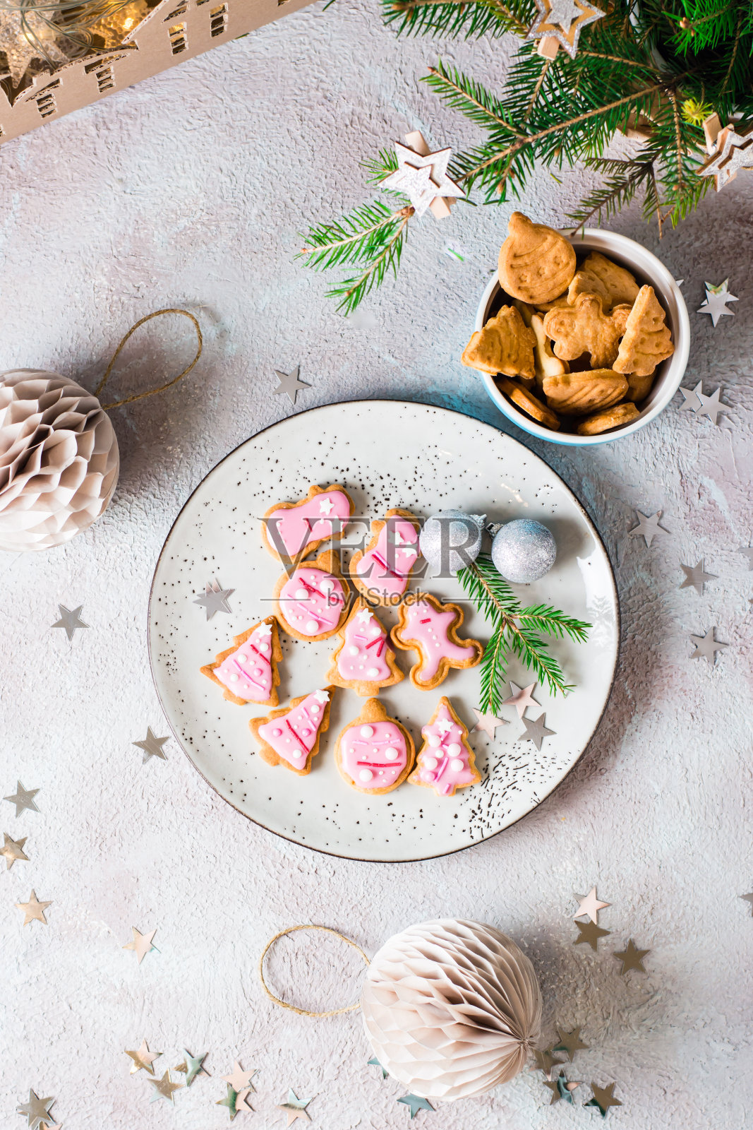 在装饰好的桌子上,盘子里放着新鲜出炉的圣诞饼干和粉红色的糖霜。节日的治疗。顶部和垂直视图。特写镜头照片摄影图片