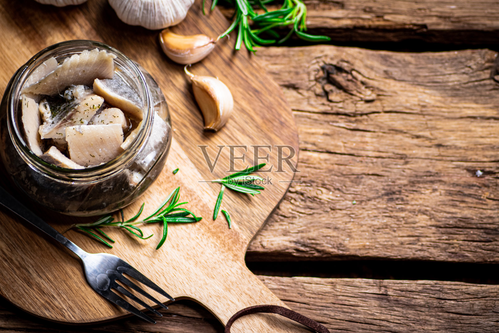 盐渍鲱鱼片放在玻璃罐里,放在切菜板上照片摄影图片