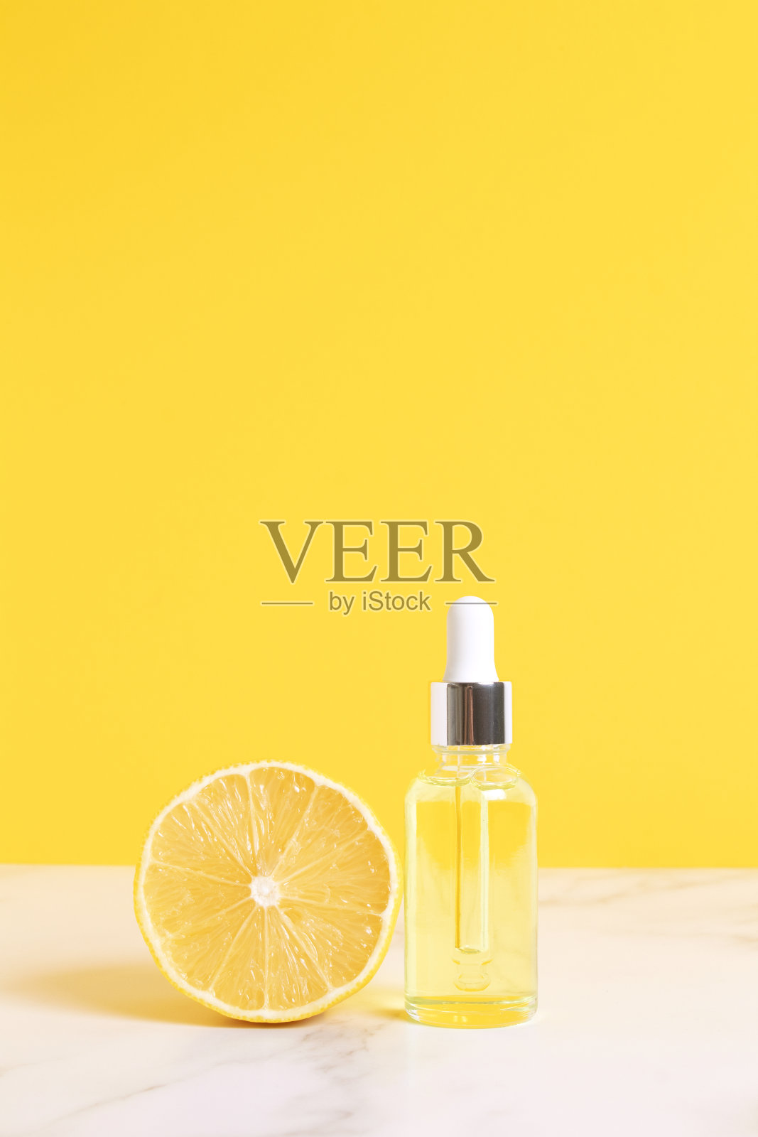 维生素c柠檬精油精华。带吸管的玻璃瓶,黄色底色上放半个柠檬。健康美丽理念。有机天然化妆品照片摄影图片
