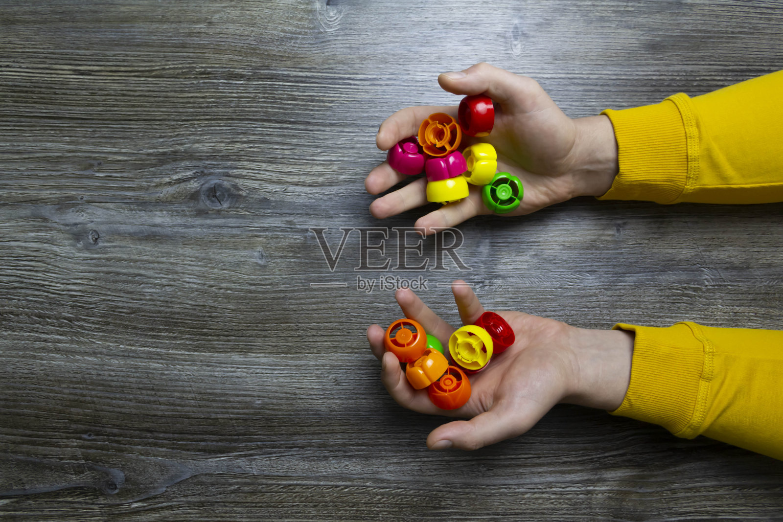 我们收集垃圾、塑料插头和塑料来拯救我们的星球、自然和环境。男人们的手躺在一个灰色的木质表面上,它被用作背景或带有入射光的表面。照片摄影图片