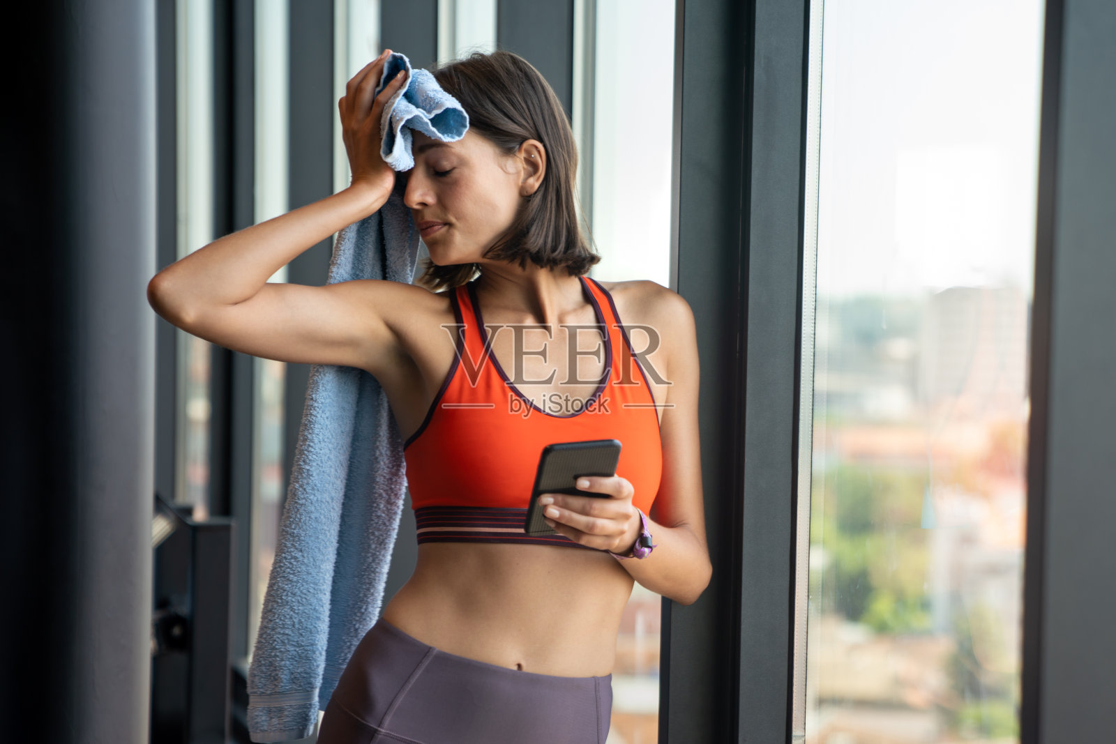 一个快乐的女运动员在健身房使用智能手机的肖像照片摄影图片