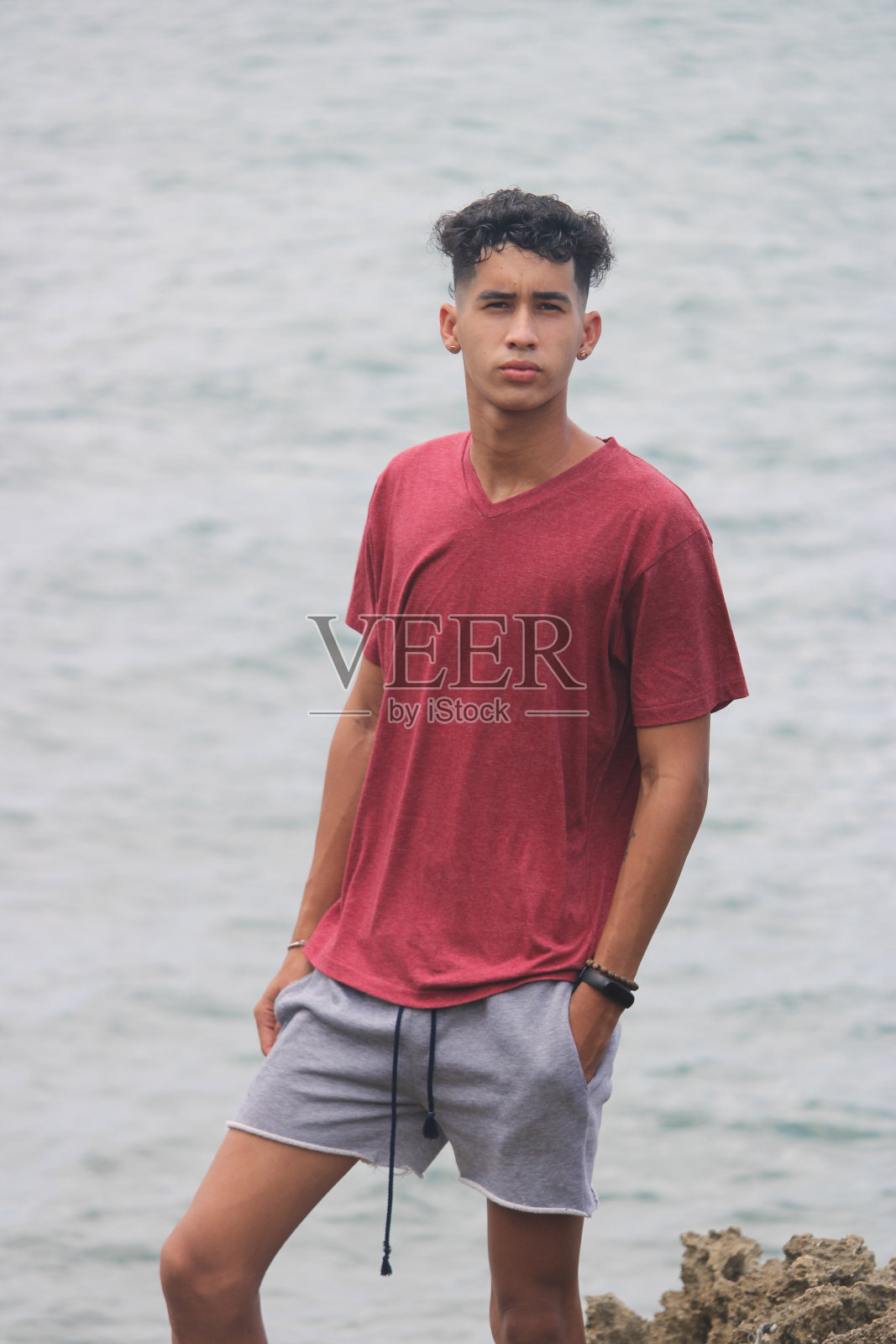 一个穿着红色套头衫的年轻人在海滨穿着灰色套头衫享受生活照片摄影图片