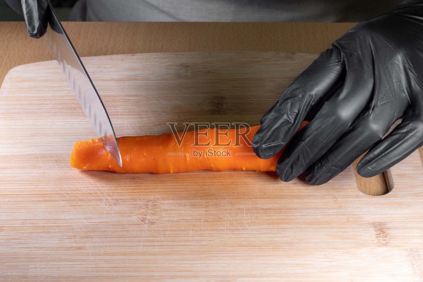 厨师的手在黑色手套拿着刀和切熟胡萝卜剥皮厨房木野猪照片摄影图片