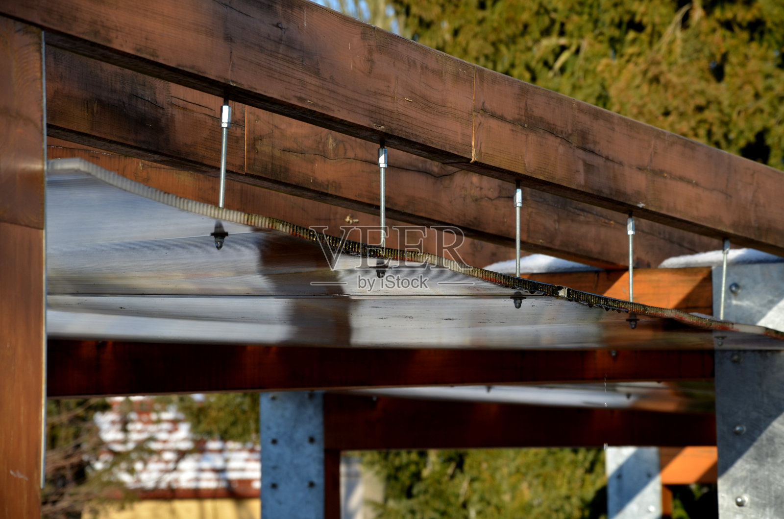 在公园的树篱后面矗立着一个由景观设计师用棕色木材建造的新藤架。两边都是木树篱所有的长椅都被雪覆盖着照片摄影图片