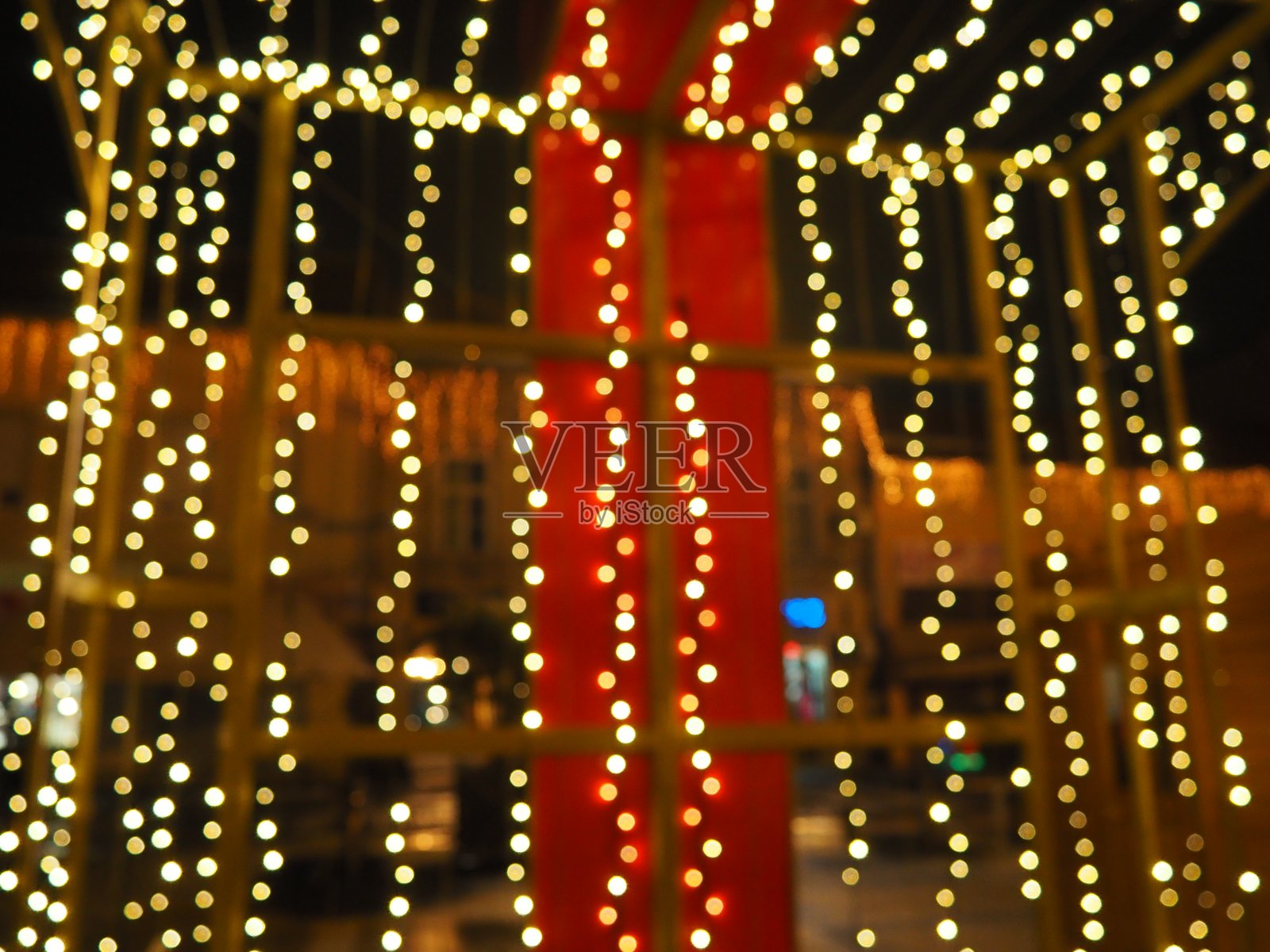 美丽的花环装饰着市中心。新年和圣诞的街道装饰。黑暗中闪烁着无数黄色和白色的灯泡。五彩装饰设计和散景。照片摄影图片