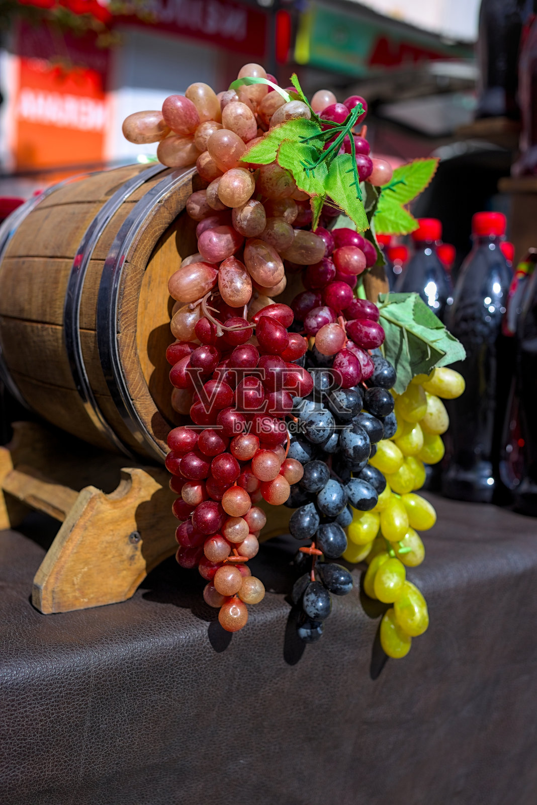 几串白色、粉色和黑色的葡萄在一个旧木桶上。照片摄影图片
