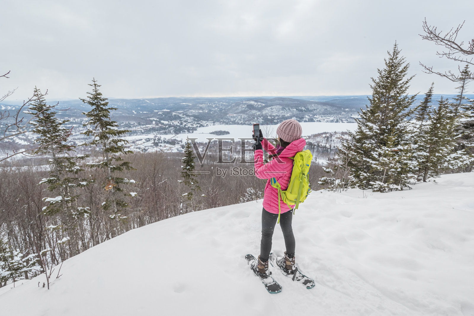 电话。徒步雪鞋妇女在冬季森林使用手机应用程序拍摄田径性的冬季景观。人们在雪中徒步旅行,过着积极的生活方式。蒙特特朗布兰特,劳伦提斯,加拿大魁北克。照片摄影图片