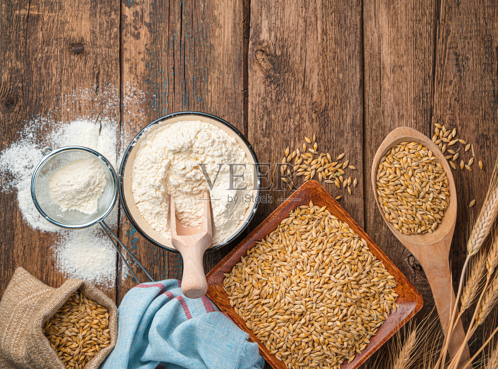 面粉放在碗里,小麦和小穗放在木制的背景上照片摄影图片