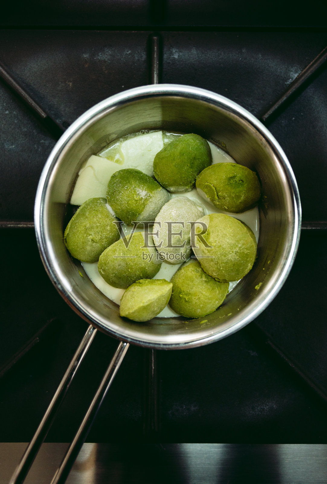 冷冻菠菜在锅里-准备煮。冷冻菠菜绿球-烹饪概念。照片摄影图片